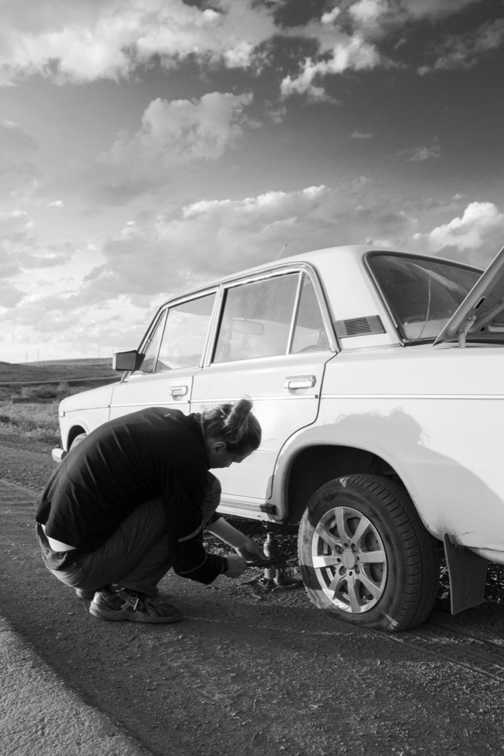 Persona cambiando la llanta de un vehículo a la orilla de la carretera