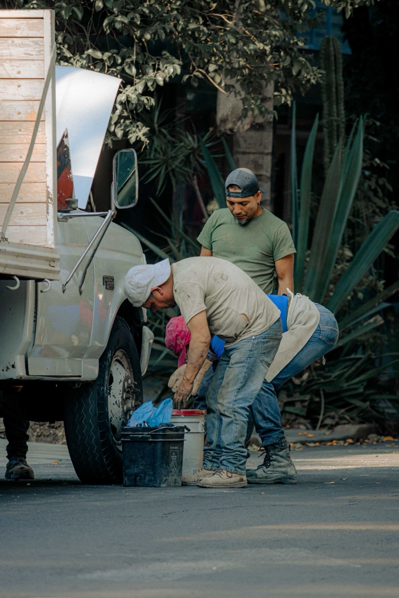 Dos personas reparando la llanta de un camión a la orilla del camino